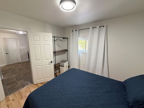 Ein Schlafzimmer mit einem Bett, einem Kleiderschrank, einem Heizkörper und einem fenster mit Vorhängen.