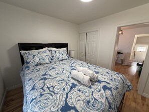 Ein Schlafzimmer mit einem Bett, weißen Wänden, einem Holzboden und einer weißen Tür.
