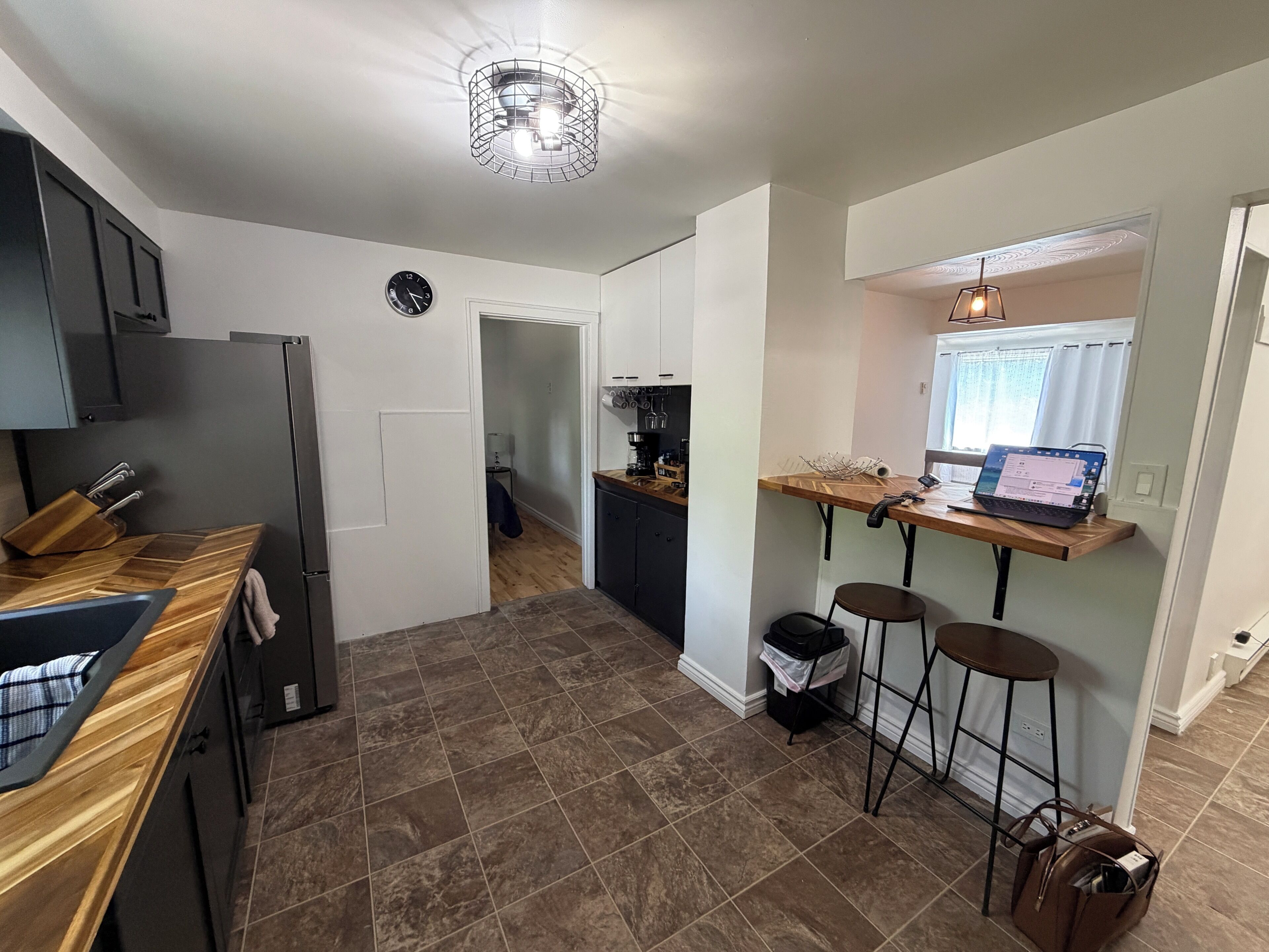 Eine moderne Küche mit Holzausziehtisch, einem eingebauten Backofen und einem Essbereich mit einem Laptop auf einem Holztisch.