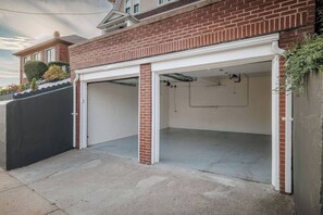 A residential garage with a brick facade and a white garage door. - Luxury Designer Suite 2BR• Boston • Sunroom (Boston)