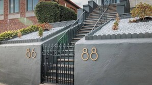 A gated entrance with numbers 86 and 88, a staircase, and a hedge. - Luxury Designer Suite 2BR• Boston • Sunroom (Boston)