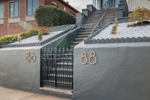 A gated entrance with numbers 86 and 88, a staircase, and a hedge. - Luxury Designer Suite 2BR• Boston • Sunroom (Boston)
