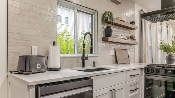 A modern kitchen with a stainless steel range, a double sink, and a window with a view of greenery outside. - Luxury Designer Suite 2BR• Boston • Sunroom (Boston)