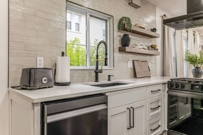 Cuina moderna amb forlla d'acer inoxidable, un doble safata i una finestra amb vista a la vegetació.