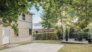 A residential backyard with a paved patio, a wooden deck, and a fenced area with a bench. - Luxury Designer Suite 2BR• Boston • Sunroom (Boston)