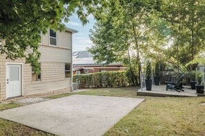 A residential backyard with a paved patio, a wooden deck, and a fenced area with a bench. - Luxury Designer Suite 2BR• Boston • Sunroom (Boston)