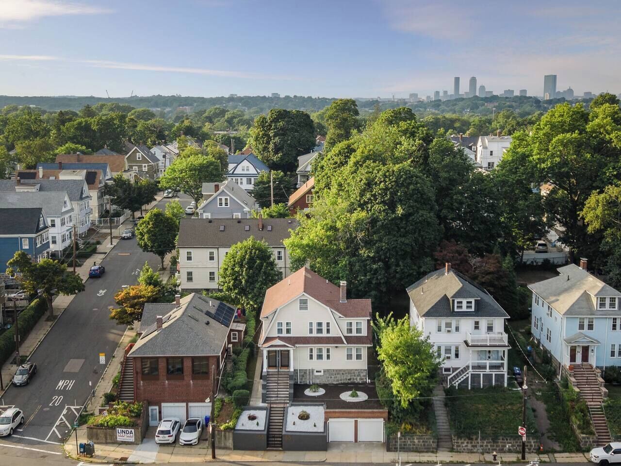 A residential area with houses, a street, and a distant city skyline.
