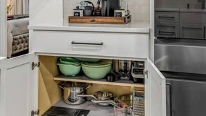 A kitchen with open cabinets displaying dishes, glasses, and kitchenware. - Luxury Designer Suite 2BR• Boston • Sunroom (Boston)