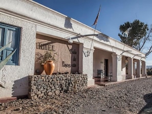 Un edificio con fachada de piedra, un jarrón grande y una bandera.