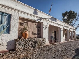 Un edificio con fachada de piedra, un jarrón grande y una bandera.