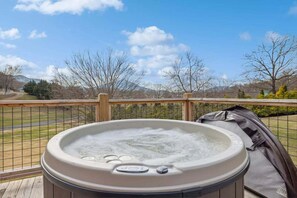 Un bain à remous sur une terrasse en bois, avec vue sur une route et des arbres en arrière-plan.