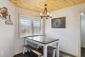 A room with a wooden ceiling, a table with a bench, a window with blinds, and a wall-mounted light fixture. - Majestic Valley View: Dog Friendly w/ Fenced Yard, 3 Kings & Hot Tub (Sevierville)