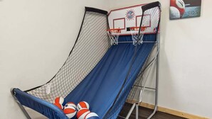 Un aro de baloncesto con red, un tobogán azul y varias pelotas de baloncesto.