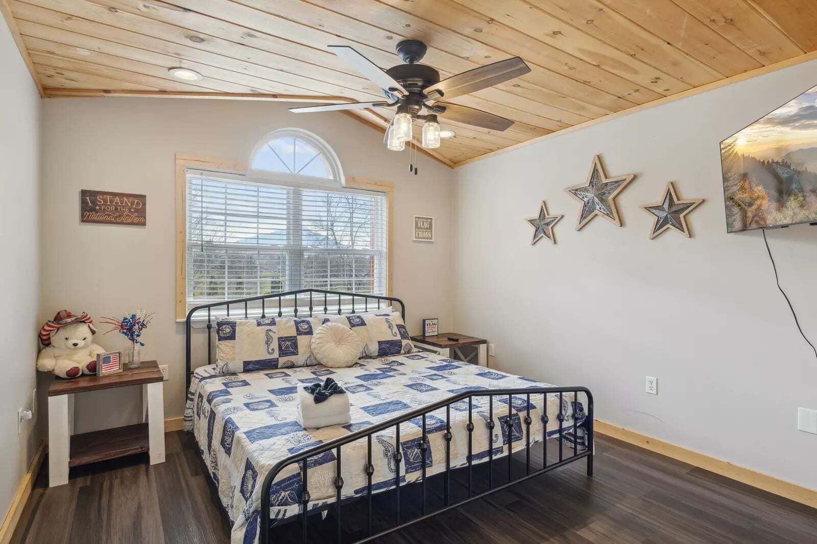 Un dormitorio con cama, ventilador de techo, ventana y una pared decorada con estrellas.