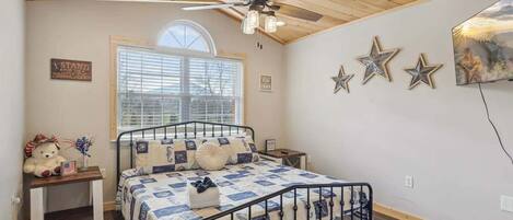 Un dormitorio con cama, ventilador de techo, ventana y una pared decorada con estrellas.