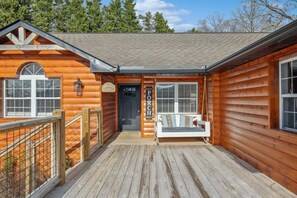 A wooden cabin with a porch, a welcome sign, and a swing seat. - Majestic Valley View: Dog Friendly w/ Fenced Yard, 3 Kings & Hot Tub (Sevierville)