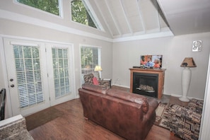 A living room with a fireplace, a sofa, a television, and a patterned rug. - Viewcatcher: Gatlinburg 2BR A-Frame Cabin w/ Mountain Views, Hot Tub & Resort Pools (Gatlinburg)