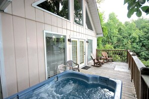 Terraza con jacuzzi, asientos exteriores y vista a un bosque.