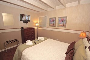 Una habitación de hotel con una cama, un aparador, un televisor y dos cuadros en la pared.