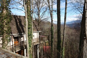 A two-story house with a balcony, surrounded by trees and a mountainous backdrop. - Viewcatcher: Gatlinburg 2BR A-Frame Cabin w/ Mountain Views, Hot Tub & Resort Pools (Gatlinburg)