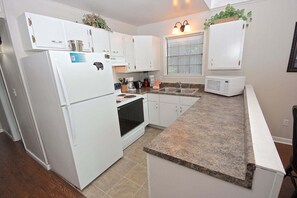 A kitchen with white cabinets, a granite countertop, a stove, a sink, and a microwave. - Viewcatcher: Gatlinburg 2BR A-Frame Cabin w/ Mountain Views, Hot Tub & Resort Pools (Gatlinburg)