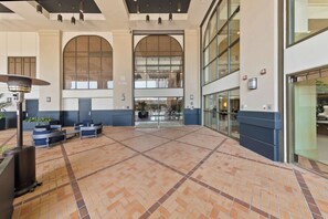 Eine großzügige Lobby mit Fliesenboden, Sitzgelegenheiten und großen Fenstern.