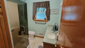 Une salle de bain comprenant des toilettes, un lavabo et un espace douche.