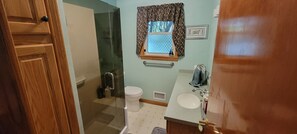 Een badkamer met toilet, wastafel en douchehoek.