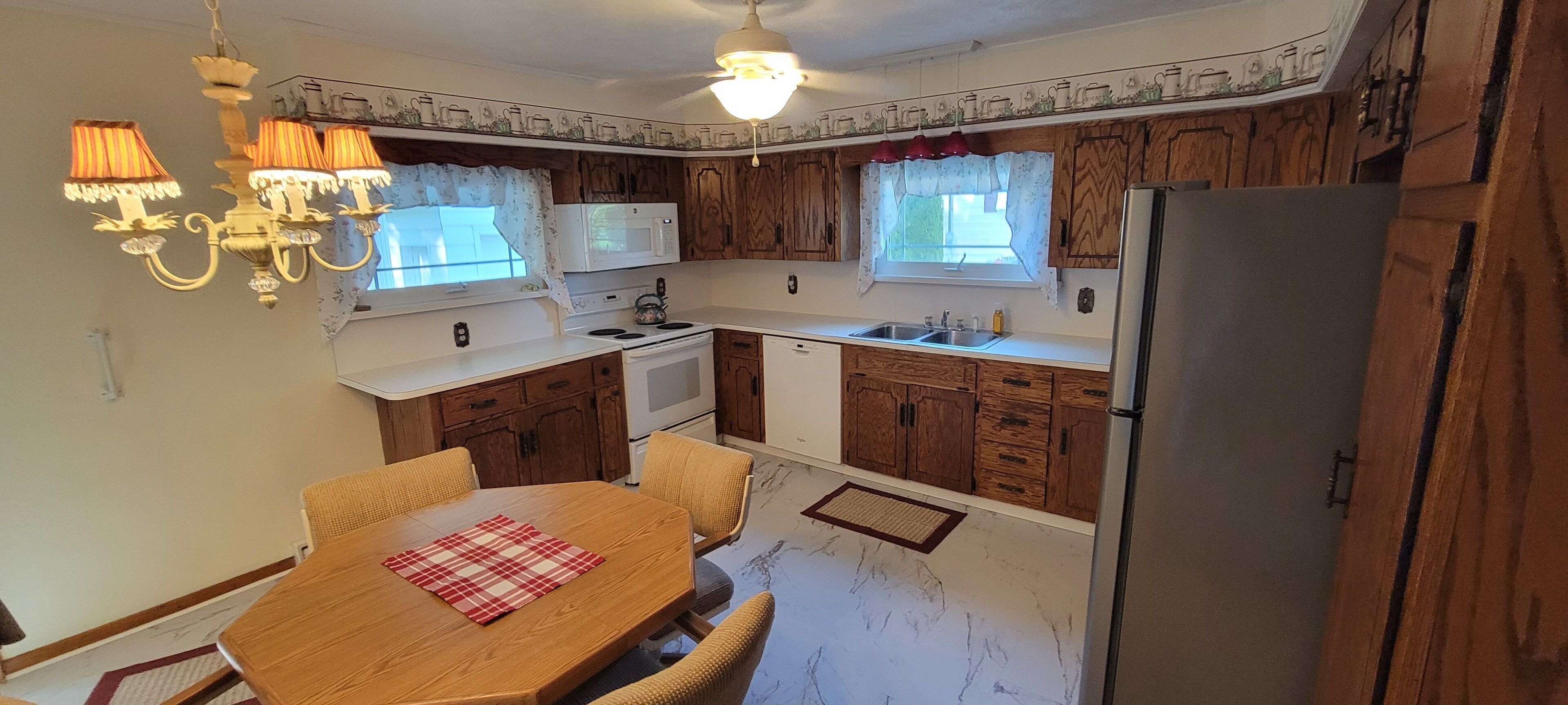 Una cocina compacta con gabinetes de madera, microondas, estufa, fregadero y refrigerador.