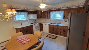 Una cocina compacta con gabinetes de madera, microondas, estufa, fregadero y refrigerador.