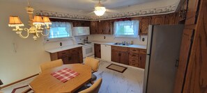 Eine kleine Küche mit Holzschränken, einer Mikrowelle, einem Herd, einem Spülbecken und einem Kühlschrank.