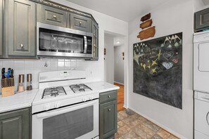 A kitchen with a gas stove, microwave, and a chalkboard wall with a welcome message. - Calm & Cozy Cabin - Cabin Retreat w/Spa & Large Fenced Yard (Big Bear City)
