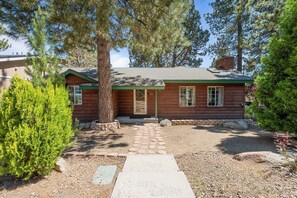 A wooden cabin with a front porch, a chimney, and a stone pathway leading to the entrance. - Calm & Cozy Cabin - Cabin Retreat w/Spa & Large Fenced Yard (Big Bear City)