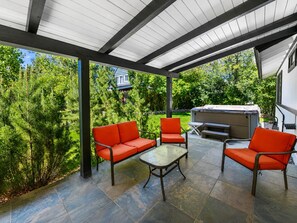 An outdoor patio with a covered area, stone flooring, and outdoor furniture.