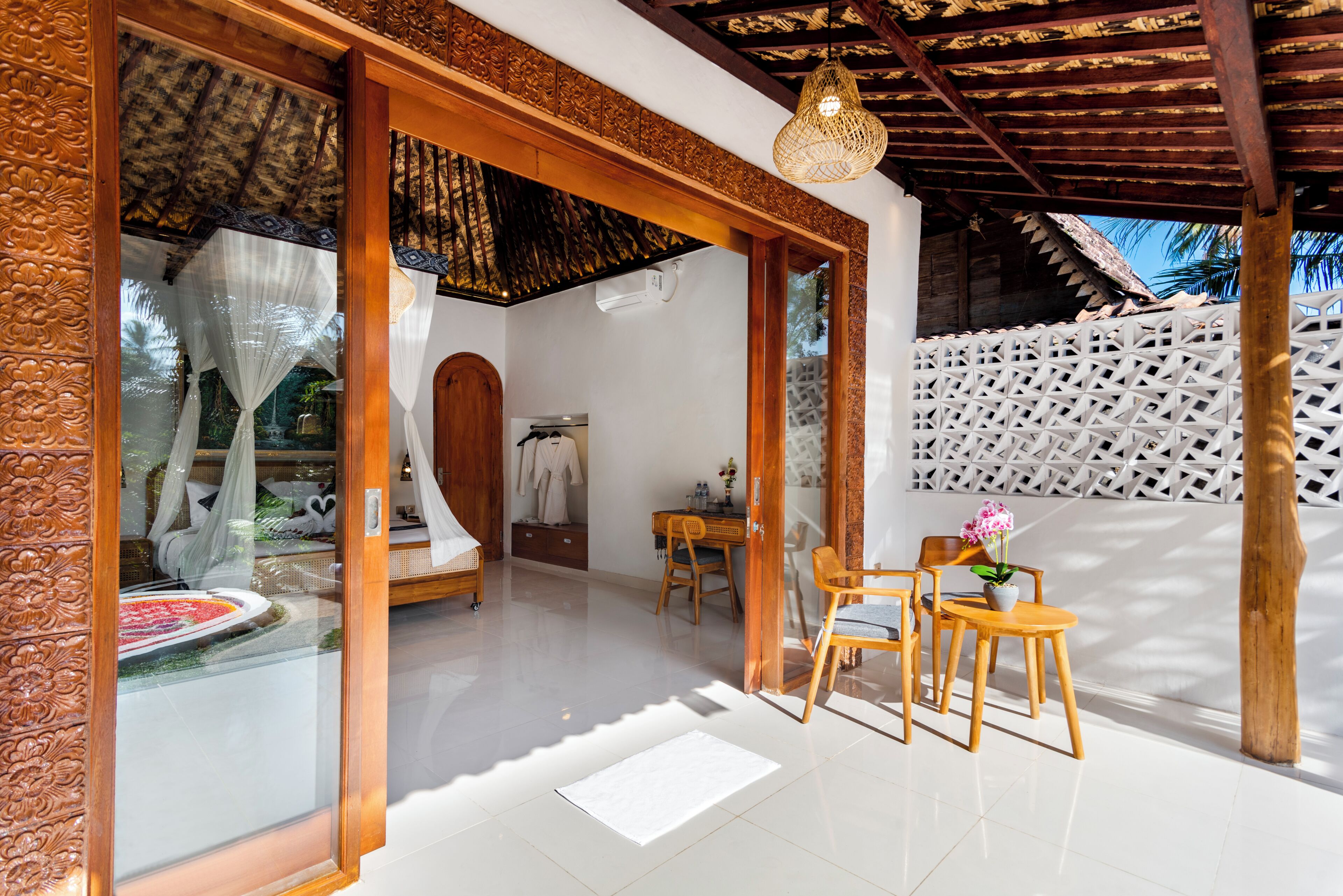 A room with a bed, a sitting area with chairs and a table, and a view of the outdoors.