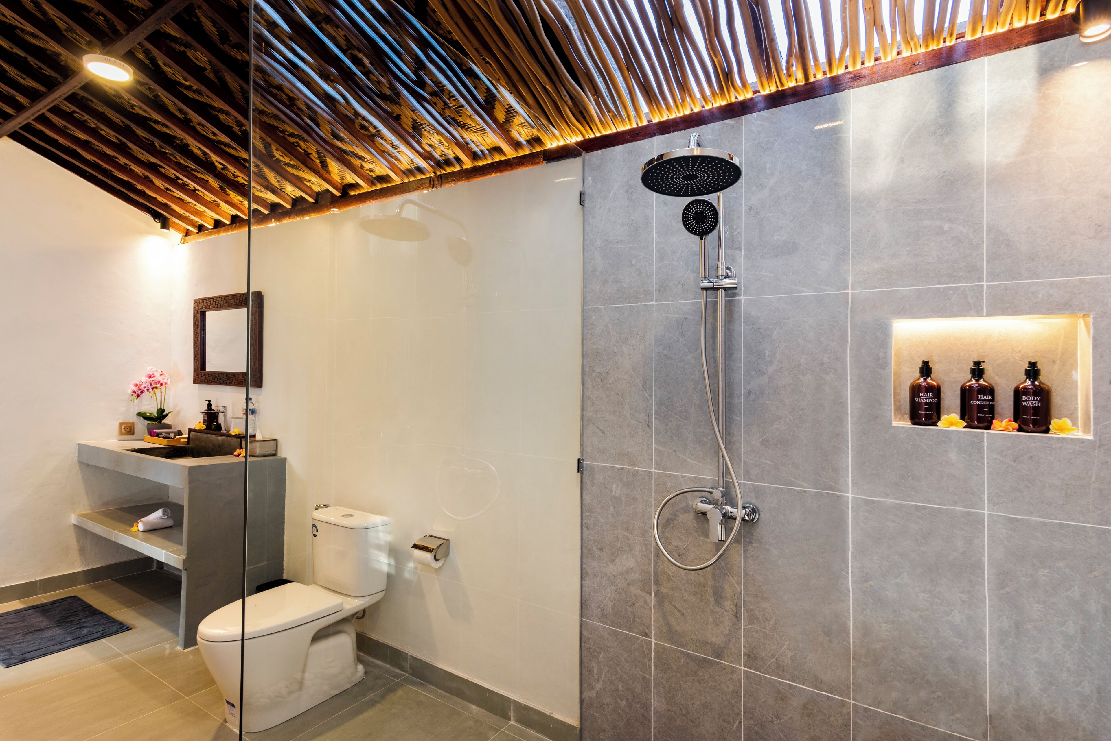 A modern bathroom with a shower, toilet, and a vanity with a mirror.