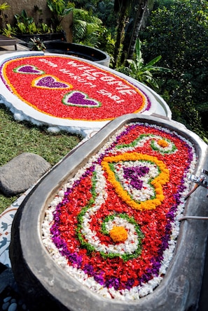 Un arreglo floral tradicional en una cuenca de metal, rodeado de follaje.