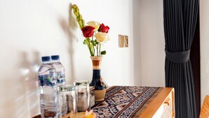 A dining table with a patterned tablecloth, a vase with flowers, and various items on the table.