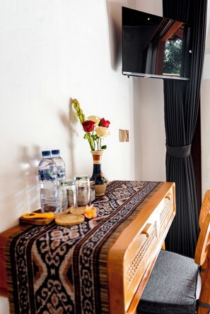 Una mesa de comedor con mantel estampado, un jarrón con flores y varios objetos sobre la mesa.