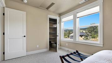 A bedroom with a bed, a window with a view, a closet, and a door.