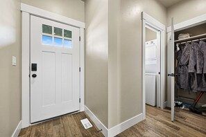 A hallway with a white door, a laundry area with a washing machine, and a closet with hanging clothes.