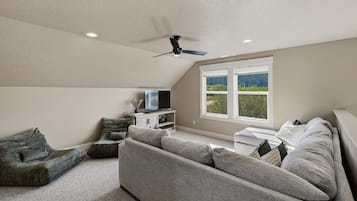 Un salon moderne avec un canapé gris, un téléviseur et un ventilateur de plafond.