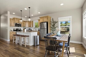 A modern kitchen with wooden cabinets, stainless steel appliances, and a dining area with a wooden table and chairs.
