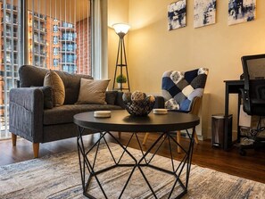 A modern living room with a sofa, a coffee table, and a chair. There is a floor lamp and artwork on the wall. - New Amazon HQ Pentagon Fashion Centre (Arlington)