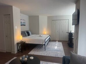 A bedroom with a bed, bedside table, lamp, and a small decorative item on the floor. - New Amazon HQ Pentagon Fashion Centre (Arlington)