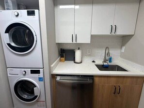 A compact kitchen with a washing machine, dishwasher, and a sink with a faucet. - New Amazon HQ Pentagon Fashion Centre (Arlington)