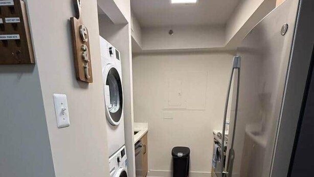 A laundry room with a washing machine, dryer, and a trash bin. - New Amazon HQ Pentagon Fashion Centre (Arlington)