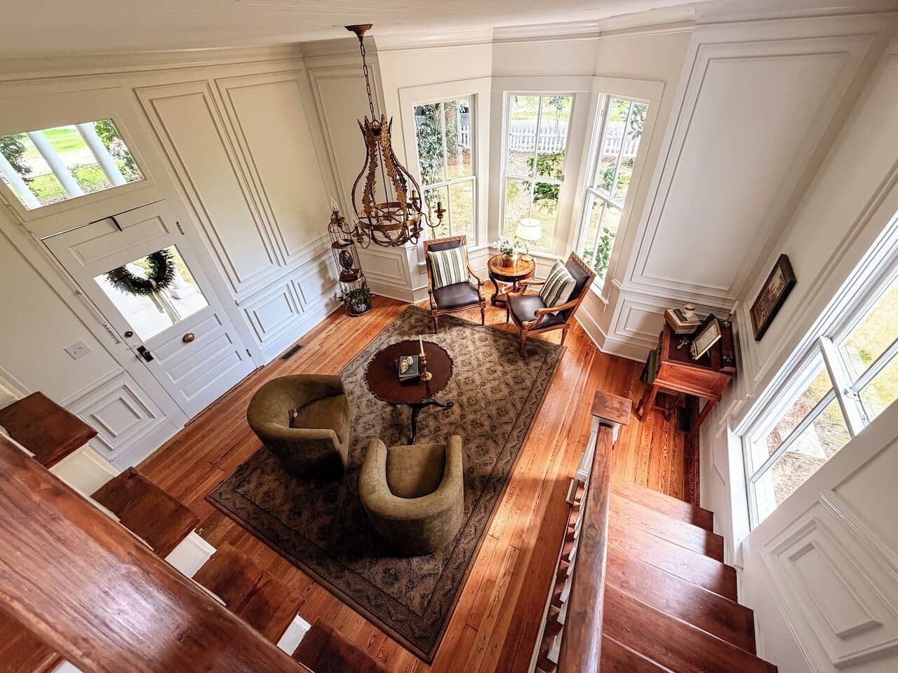 Une pièce spacieuse dotée d’un plancher en bois, d’un grand tapis et d’un coin salon avec une table et des chaises.