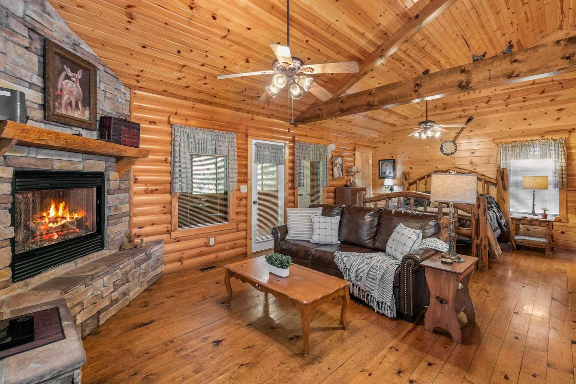 A log cabin interior with a fireplace, a ceiling fan, a sofa, and a coffee table.