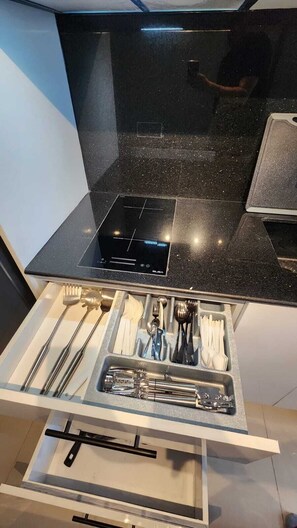 A kitchen with a black countertop, a built-in stove, and a drawer with utensils. - Cebu JTower Sky Luxe Ocean View Suite 15 Min Airport With VPN, Pool, Karaoke &.. (Mandaue)